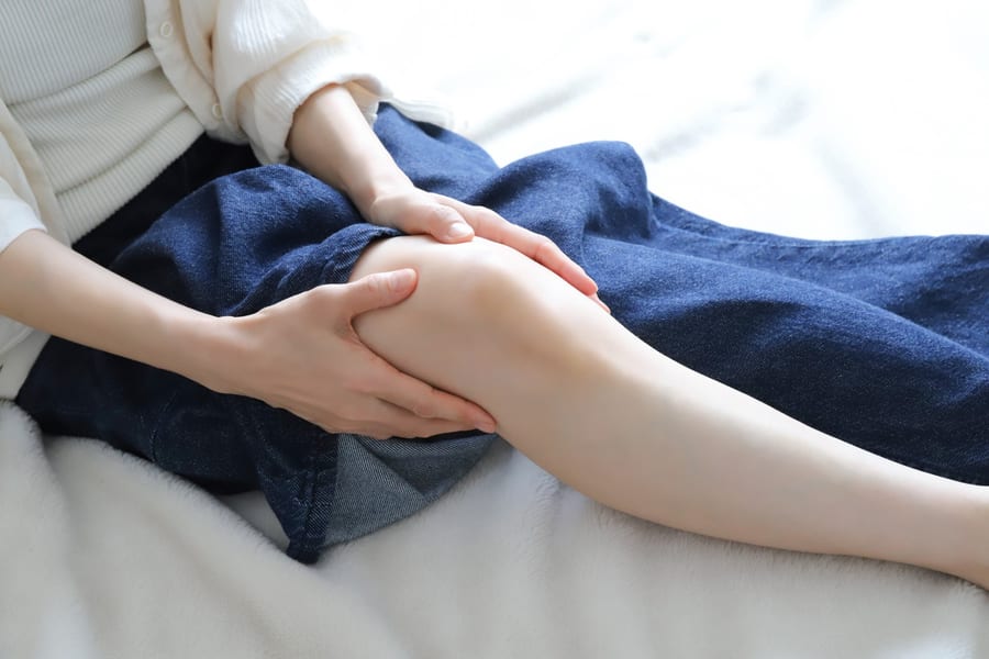 ソファに座り、両手で膝を押さえている人